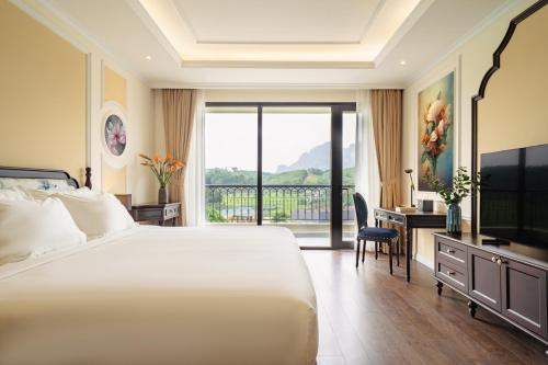 une chambre d'hôtel avec un lit, un bureau et une fenêtre dans l'établissement Venusgiti Hot Spring Resort & Spa, à Hòa Bình