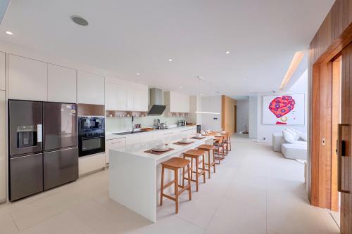 a kitchen with white cabinets and a long island with bar stools at Designer 3BR Pool Villa in New Build LuxPride 4 L8 Residence in Bang Tao Beach