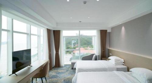 a hotel room with two beds and a large window at Grand Nest Hotel (Tang Jia Wan Beach) in Zhuhai