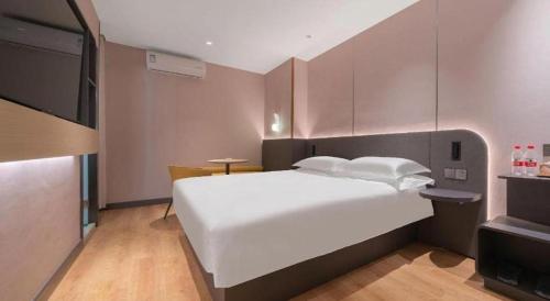 a bedroom with a large white bed and a television at Jinjiang Inn Quanzhou West Street Kaiyuan Temple in Quanzhou