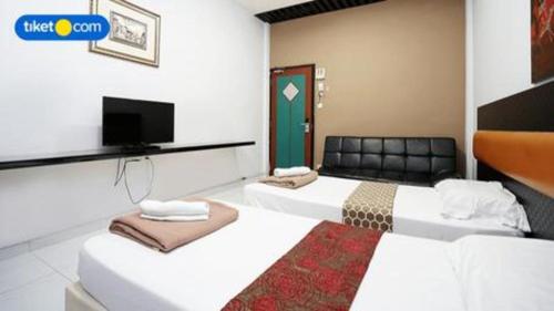 two white beds in a room with a tv at Lai Ming Hotel Cosmoland in Singapore