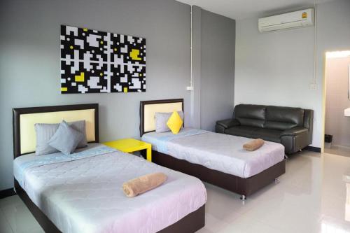 a room with two beds and a chair and a couch at Nithra Ratree Hotel in Si Maha Phot