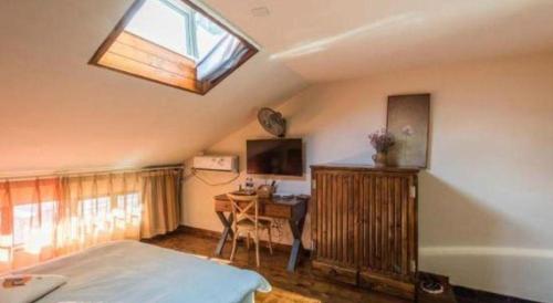 a bedroom with a bed and a desk and a window at Dali Four Seasons Hostel in Dali Ancient Town