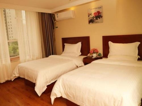 two beds sitting next to each other in a bedroom at GreenTree Inn Luoyang Zhongzheng Street Express Hotel in Luoyang