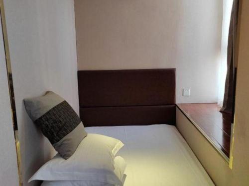 a small bedroom with a bed with a pillow at GreenTree Inn Luoyang Zhongzheng Street Express Hotel in Luoyang