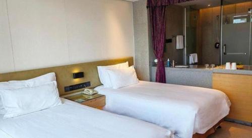 a hotel room with two beds and a bathroom at New Century Kylie Hotel Ningbo in Ningbo