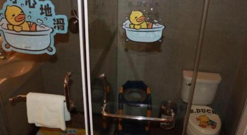 a bathroom with a shower with simpsons stickers on the wall at New Century Kylie Hotel Ningbo in Ningbo