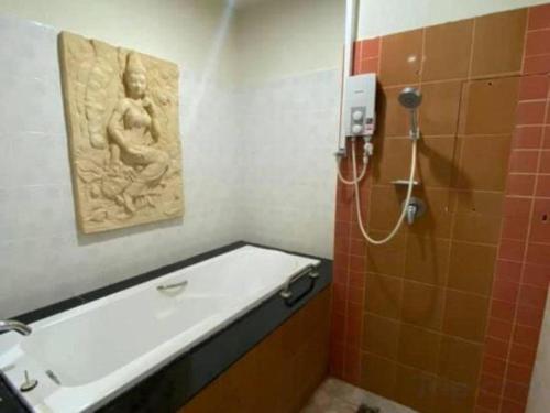 a bathroom with a bath tub and a statue on the wall at AmornSukhothai Hotel in Sukhothai