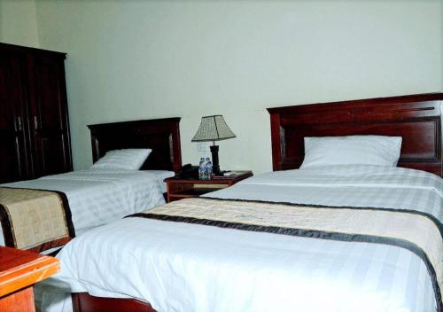 a bedroom with two beds and a table with a lamp at Hai Au Hotel in Hai Phong