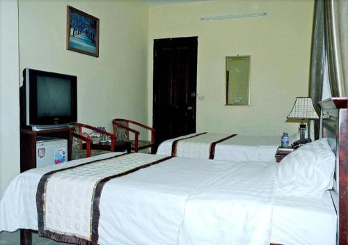 a hotel room with two beds and a flat screen tv at Hai Au Hotel in Hai Phong