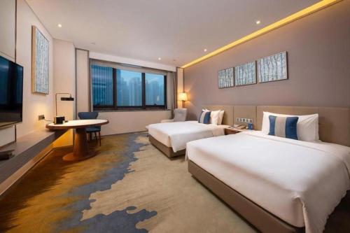 a hotel room with two beds and a flat screen tv at Rosedale Hotel Taicang in Taicang