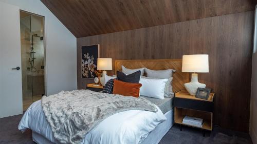 a bedroom with a large bed with a wooden wall at Peak Chalet in Mount Hotham