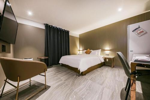a hotel room with a bed and a television at Cheongju Maryjane Hotel in Cheongju