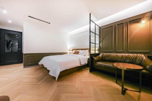 a bedroom with a bed and a leather couch at Cheongju Maryjane Hotel in Cheongju