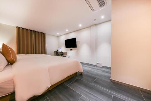 a hotel room with a bed and a tv at Cheongju Maryjane Hotel in Cheongju
