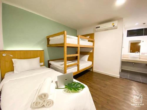 a bedroom with a bed with a laptop and bunk beds at Need a Nap Hostel Phrae in Phrae