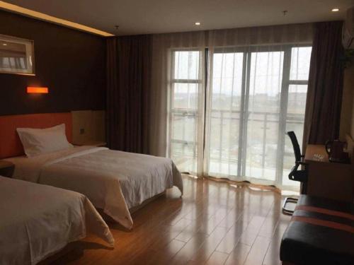 a hotel room with two beds and a large window at 7 Days Premium Nanjing Gaochun Beiling Road Branch in Gaochun