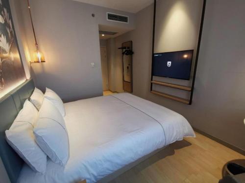 a bedroom with a white bed and a television at Jinjiang Inn Tianjin Station Jinwan Square in Tianjin