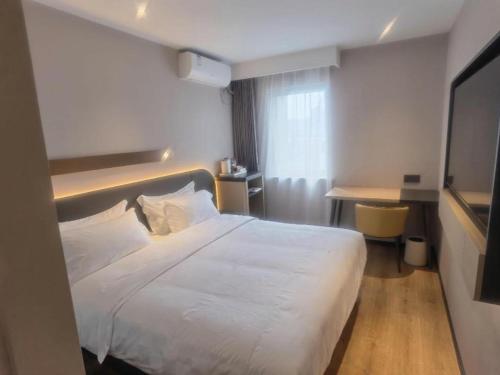a hotel room with a white bed and a desk at Jinjiang Inn Tianjin Station Jinwan Square in Tianjin