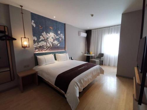 a bedroom with a large bed with a painting on the wall at Jinjiang Inn Tianjin Station Jinwan Square in Tianjin