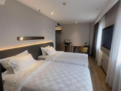 a hotel room with two beds and a flat screen tv at Jinjiang Inn Tianjin Station Jinwan Square in Tianjin