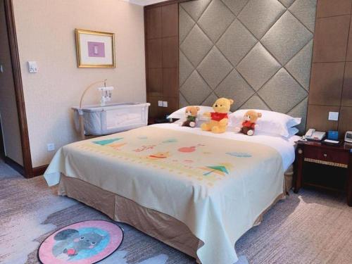 two teddy bears sitting on top of a bed at New Century Hotel Taizhou 