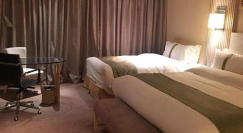 a hotel room with two beds and a glass table at Datong Hotel in Datong