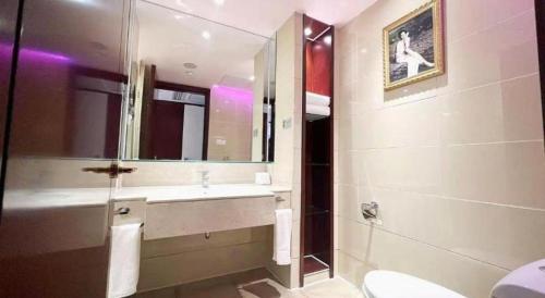 a bathroom with a sink and a toilet and a mirror at Hohhot Hai Liang Plaza Hotel in Hohhot