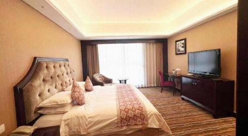 a bedroom with a large bed and a flat screen tv at Hohhot Hai Liang Plaza Hotel in Hohhot
