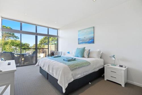 Un dormitorio blanco con una cama y un balcón. en Aqua Shores - 1 Bedroom couples stay - Wifi, Linen, Netflix and AC, en Huskisson