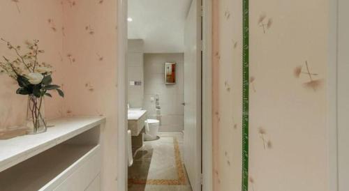 a bathroom with a toilet and a vase of flowers on a shelf at Hohhot Hai Liang Plaza Hotel in Hohhot