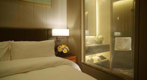 a bedroom with a bed and a bathroom with a mirror at Beijing Friendship Hotel Jing Bin Building in Beijing