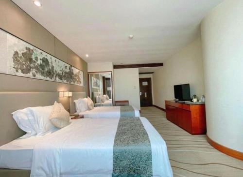 a hotel room with two beds and a television at Grand Soluxe Zhongyou Hotel Shenzhen in Shenzhen