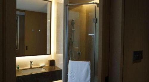 a bathroom with a shower and a sink and a mirror at Beijing Friendship Hotel Jing Bin Building in Beijing