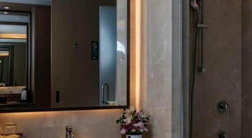 a bathroom with a mirror and a sink with flowers at Beijing Friendship Hotel Jing Bin Building in Beijing