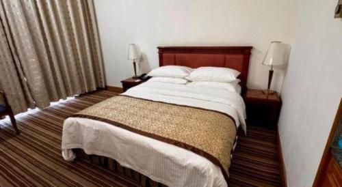 a bedroom with a large bed and two lamps at Beijing Friendship Hotel Jing Bin Building in Beijing