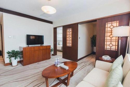 a living room with a couch and a table at Grand Soluxe Zhongyou Hotel Shenzhen in Shenzhen