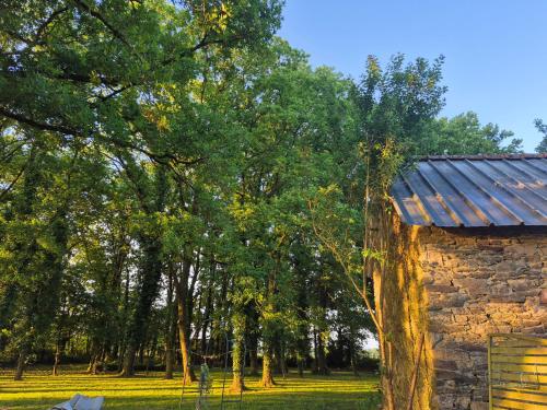 un bâtiment en pierre avec un toit en métal à côté des arbres dans l'établissement Chez Val, à Maxent
