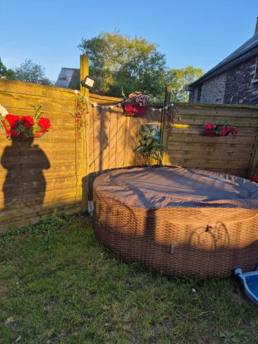 un lit en osier assis à côté d'une clôture en bois dans l'établissement Chez Val, à Maxent