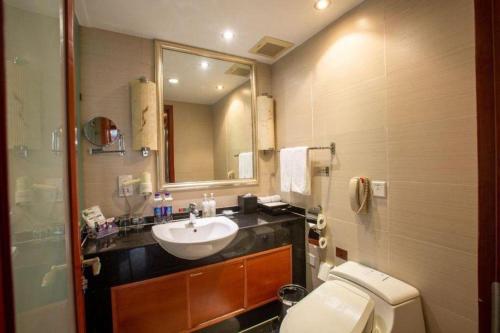 a bathroom with a sink and a toilet and a mirror at Linyi Blue Horizon Intenational Hotel in Linyi
