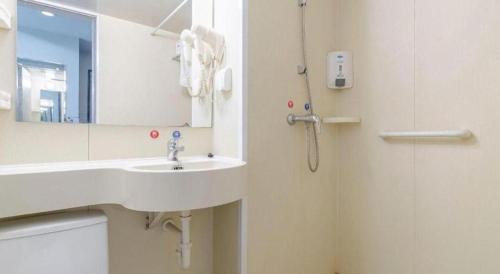 a bathroom with a sink and a mirror and a shower at Jinjiang Inn Weihai High Speed Qingdao South Road in Weihai