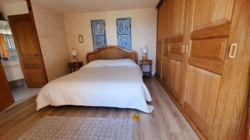 - une chambre avec un lit doté de draps blancs et de placards en bois dans l'établissement Lou Caliandro, à La Celle-sous-Gouzon