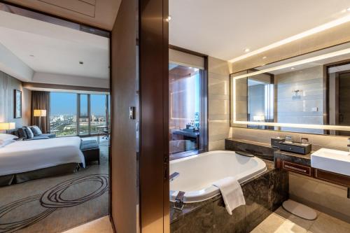 a bathroom with a tub and a bedroom with a bed at Yancheng Jinying Shangmei Hotel in Yancheng