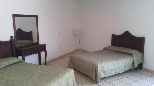a bedroom with two beds and a mirror and a dresser at Hotel Real de Cuautla in Cuautla Morelos