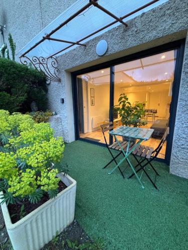 une terrasse avec une table, des chaises et des plantes dans l'établissement Appartement chez maison hôte rez de jardin, à Charmeil