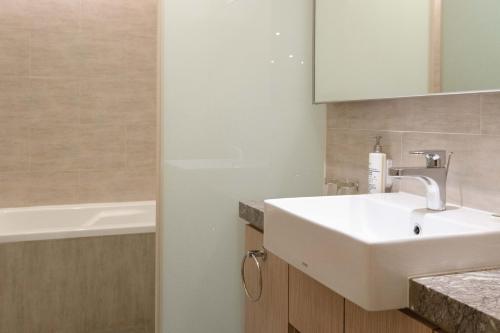 a bathroom with a white sink and a bath tub at 塔木德酒店 台中火車站館 Talmud Hotel Taichung Station in Taichung