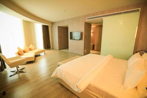 a bedroom with a bed and a chair and a television at Jinjiang Metropolo Hotel - Turpan Administration Center in Turfan