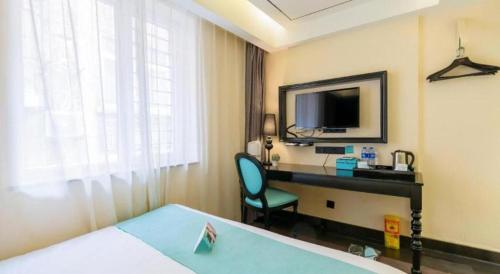 a hotel room with a bed and a desk with a television at Xana Hotelle· Tianjin Railway Station Jinwan Square Binjiang Avenue in Tianjin