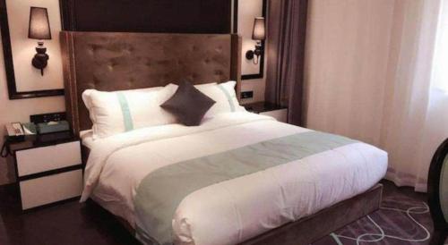 a bedroom with a large bed with a wooden headboard at Xana Hotelle· Tianjin Railway Station Jinwan Square Binjiang Avenue in Tianjin