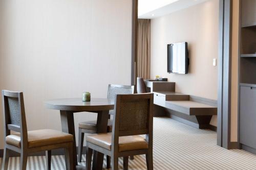 a room with a table and chairs and a television at 塔木德酒店 台中火車站館 Talmud Hotel Taichung Station in Taichung